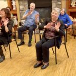 Residents sitting and holding up arms dancing